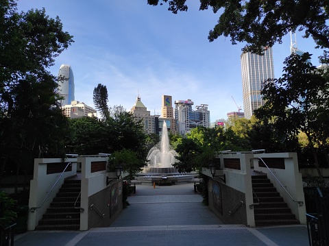 Hong Kong, July 13,2023 : View of the fountain in the Botanical and Zoological garden, Central Hong Kong, with buildings and blue sky in the background.