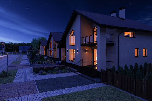 The warm glow of lights coming from warm rooms of a remote Scottish Highland croft  with a dark blue moody nighttime sky in winter in the UK.