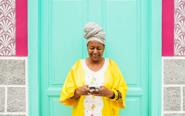 african senior woman using mobile phone while wearing traditional ethnic clothes - technology, ethnicity and mature people concept - life events laughing women latin american and hispanic ethnicity imagens e fotografias de stock