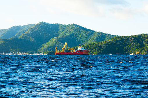 View of the coast of Trinidad Island and an offshore supply vessel anchored in the bay.