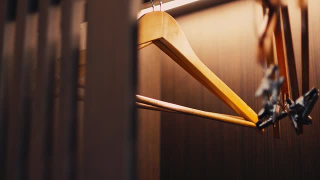 Hangers in a wooden wardrobe inside the hotel. When opening, there will be a light inside the cabinet that automatically lights up.