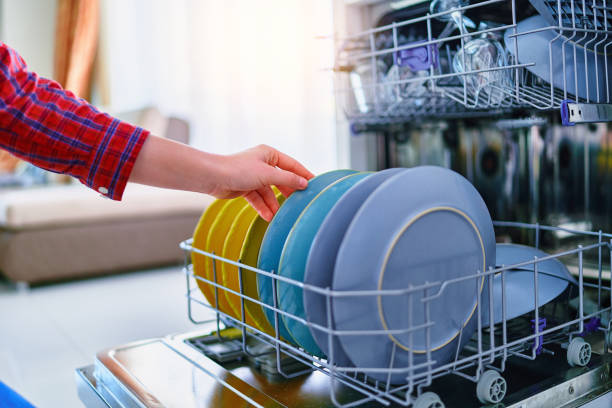 Housewife woman using modern dishwasher for wash dishes at home kitchen