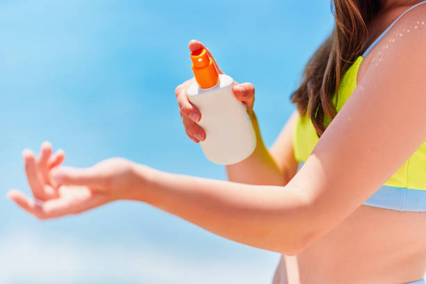 istock Female applying and holding white empty bottle blank of sunscreen lotion while sunbathing on beach by the sea in sunny summer day. Sun protection 1547817733
