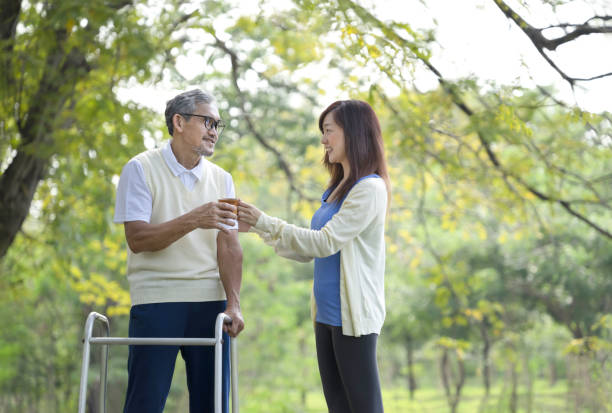 公園で散歩やピクニックに出かけながら父親に飲み物を振る舞う娘,障害者の老人が歩行器を使って歩行練習でリハビリテーション - retirement grandfather senior adult child ストックフォトと画像