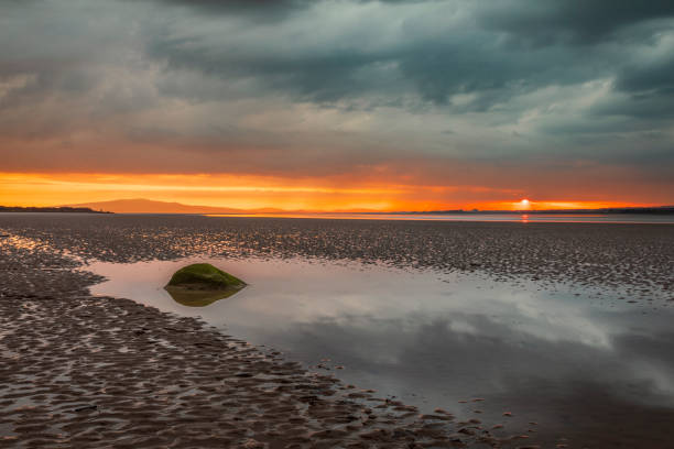 Moody dramatic skies and sunset reflections over Bowness on Solway Cumbria north east England UK