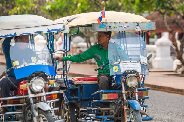 A popular public taxi transport in Laos - tuk-tuk - a motorcycle with a cab for passengers. Luang Prabang, Laos - March 03, 2023.