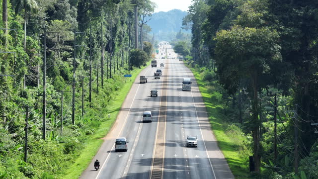 Aerial Drone of The Road Through forest of Phannga Province in Thailand, aerial drone footage with the cinematic slow panoramic camera motion across the road.