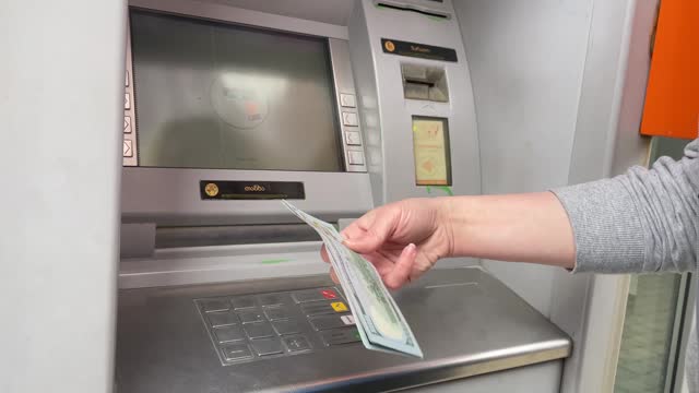 getting cash from an ATM, the cash machine gives out dollars money to a woman