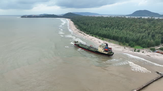 Aerial Drone view ocean waves wash large cargo ship on sandbank after storm near island shore
