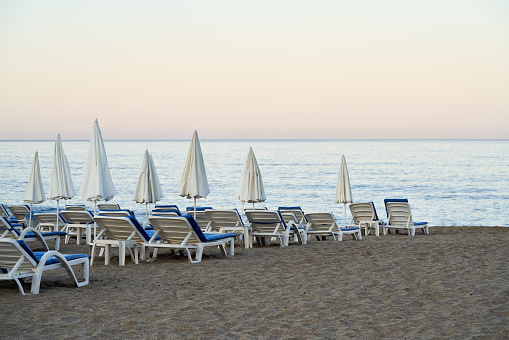 White and blue loungers on the beach near the sea in early morning