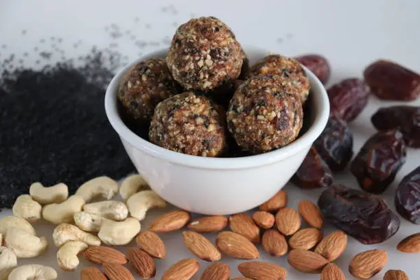 Sugar free dates and nuts ladoo. Healthy and protein rich energy balls in the shape of ladoos made from dates, almonds, cashew nuts and sesame seeds without adding any sugar. Shot on white background