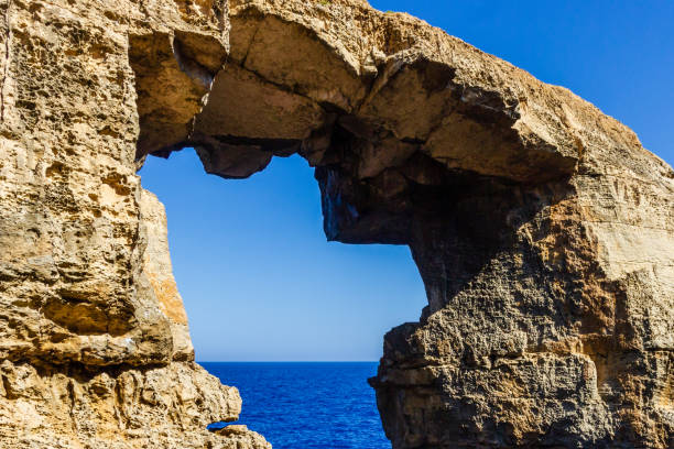The stone sea arch at wied il-Mielah, Gozo, Malta. Sunny weather, bright sunlight golden hour.