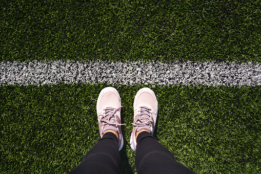 Legs of a woman standing on a sports playground behind a white starting line