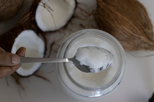 Frozen coconut oil in a glass bottle taken from refrigerator. Coconut oil is a cooking oil which freezes in the winter or in cold because it has a low melting point of approximately 24°C or 76°F.