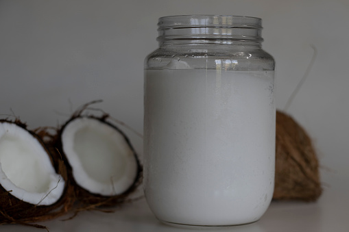 Frozen coconut oil in a glass bottle taken from refrigerator. Coconut oil is a cooking oil which freezes in the winter or in cold because it has a low melting point of approximately 24°C or 76°F.