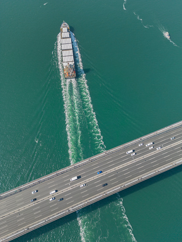 Container Ship Beneath Bridge. Aerial view of a cargo ship passing under bridge.