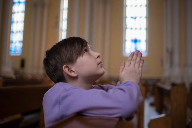 istock 10 year old child praying in a catholic church 1548051331