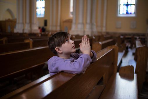 10 year old child praying in a catholic church