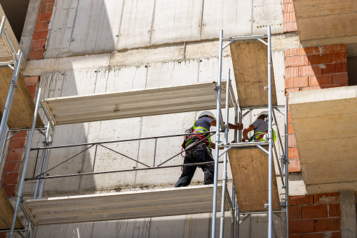 Low angle view of male Caucasian construction workers, on a scaffolding, working on a construction site