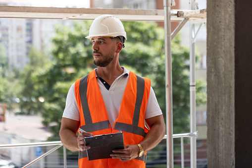 Caucasian male building contractor, architect, or engineer supervise the work on a construction site and doing the safety and quality control