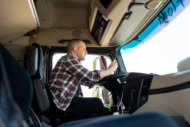 istock Transport truck driver sitting inside the cabin and using mobile 1548126034