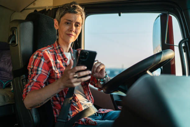 istock Female trunk driver sitting inside of a cabin and using mobile 1548129828