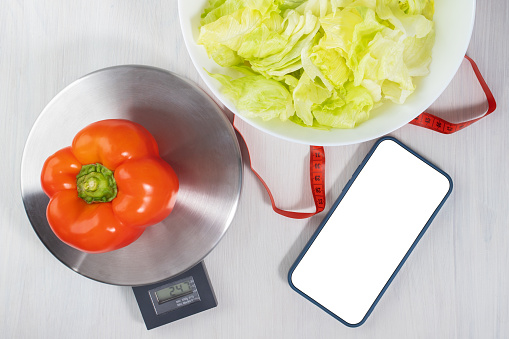 mockup phone screen on the table with groceries on the scales, diet and weight loss, calorie counting
