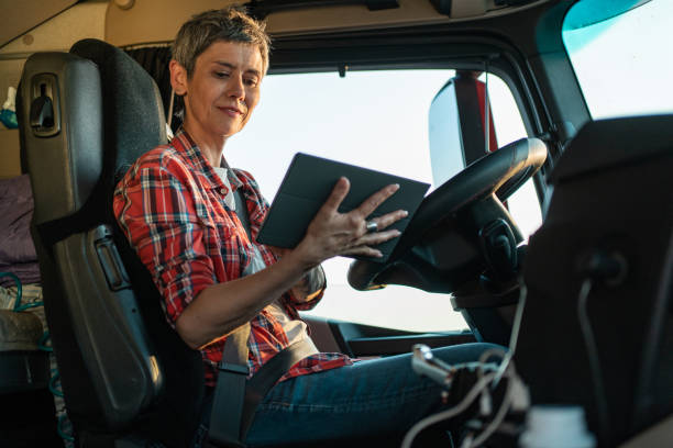 istock Female trunk driver sitting inside of a cabin and using tablet 1548132046