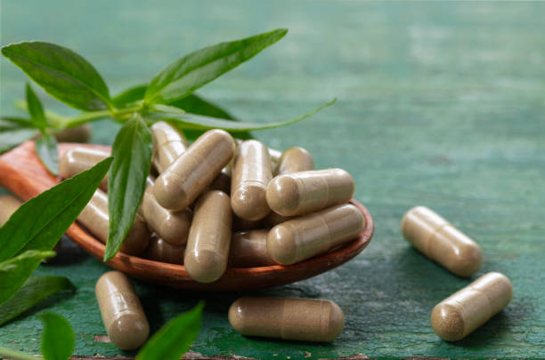 アンドログラフィスパニキュラータカプセルハーブエキスを木のスプーンに入れます。 - chinese medicine nutritional supplement herb pill ストックフォトと画像