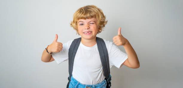 istock Primary school smiling boy girl looking at camera with backpack showing thumbs up. Copy space for advertising blank concept. Back to school. Childhood, education, products for children 1548137954