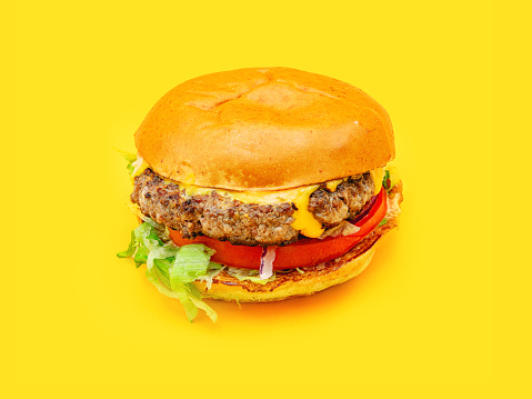 Side view from above of seamless pattern of tasty fresh juicy homemade real hamburger with beef patties, cheddar cheese, tomato, onion, and salad isolated on a yellow background with shadow