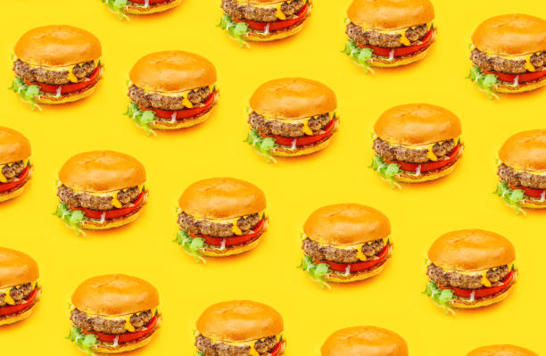 Seamless pattern burgers isolated on a yellow background Side view from above of seamless pattern of tasty fresh juicy homemade real lots of hamburgers with beef patties, cheddar cheese, tomato, onion and salad isolated on a yellow background with shadow cheese texture seamless stock pictures, royalty-free photos & images