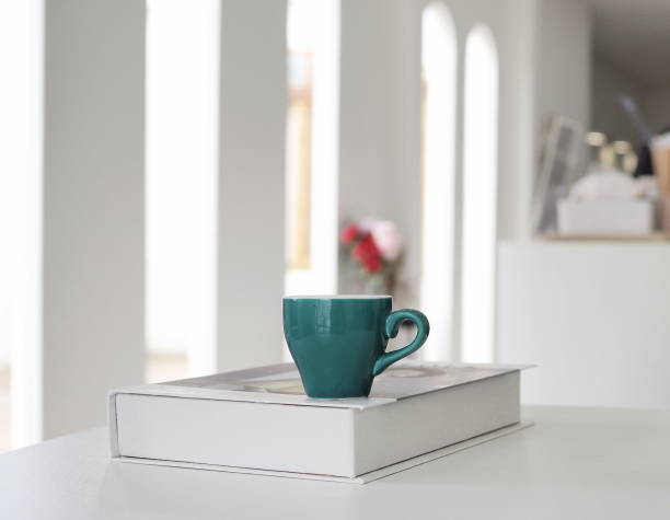 istock Cup of coffee on notebook. Glasses. At coffee shop. Blurred background. 1548156920