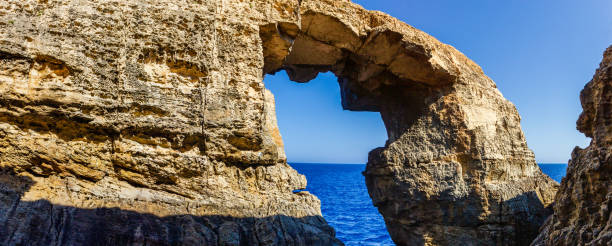 Majestic arch on cliff amid clear blue sky above stunning coastline.