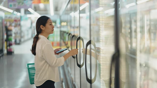 Woman shopping for food and check product details on the shelf in supermarket