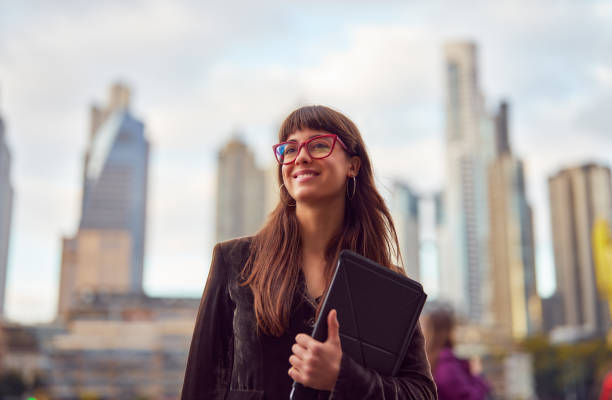 portrait beautiful young business woman in the street holding a tablet smiling stock photo