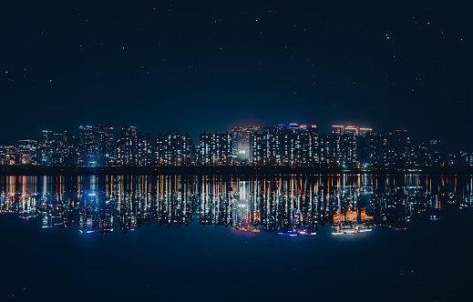 An image of the city lit up at night on the banks of the river.