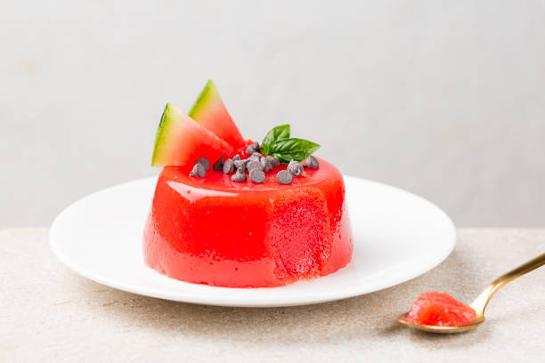 A jellied watermelon pudding, made with watermelon pulp, sugar and starch, decorated with chocolate, fresh fruit and basil leaves. Sicilian summer dessert gelo di melone. White background. stock photo