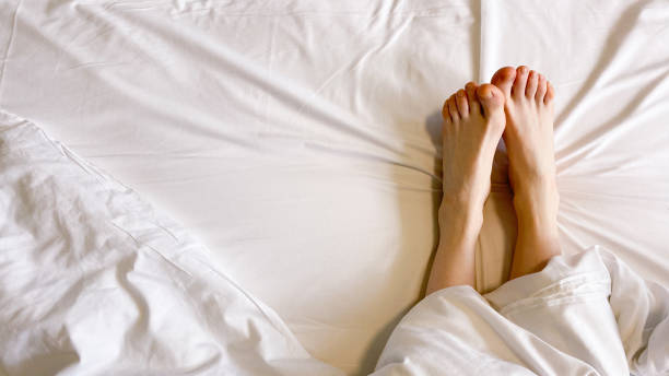 istock Women's legs on a white bed. Rest, relaxation. Meditation. Sleep. 1548307479
