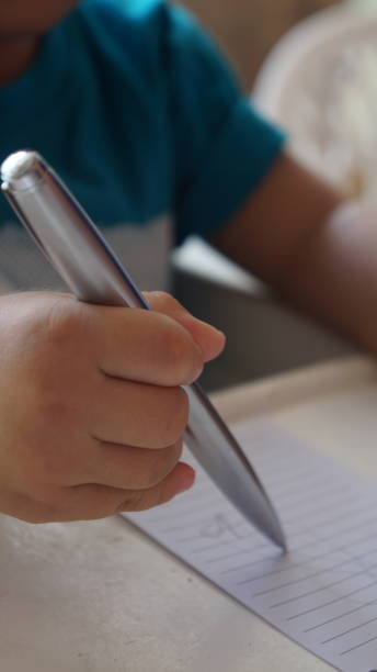 istock Child's hand writing on white paper 1548319131
