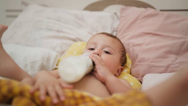 istock Small baby boy drinking milk from milk bottle in bed 1548325519