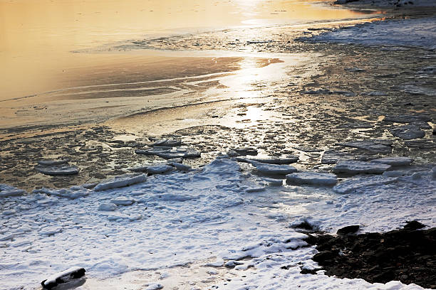 istock Sunlight on a frozen shorein winter at sunset. 154837882