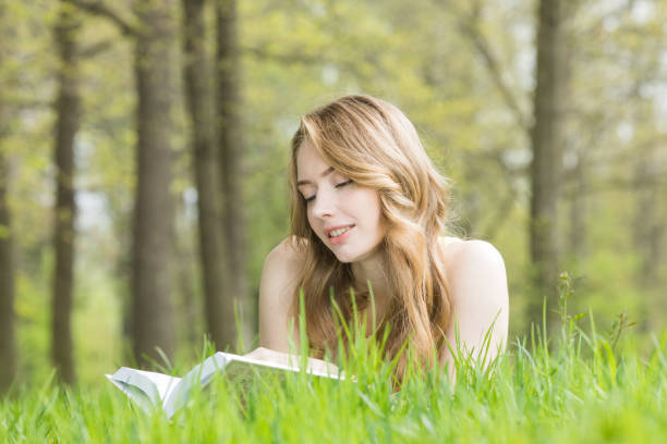 istock Woman lays on grass and reads book 1548445279