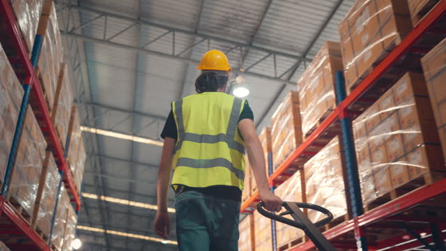 Rear view - worker working in large warehouse retail store industry, Man using hand pallet truck, People Work in product distribution logistics center. Shipment service