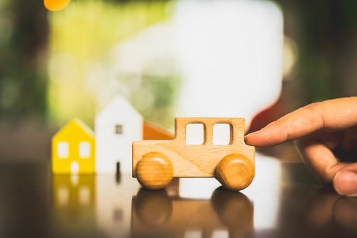 Hand holding wooden car model with sunlight, a symbol for buying a new car, vehicle car auto repair service maintenance.