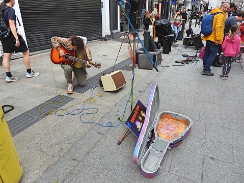 7th July 2023, Dublin, Ireland. Street entertainer busker tunning up his guitar on Grafton Street in Dublin city centre.