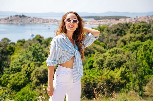 Stylish young woman posing against the background of the blue sea