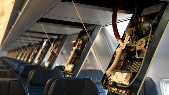 Passenger service panels dropped for maintenance in the interior of a 757 commercial Passenger airplane.