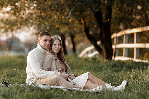 Mothers day. Stylish marriage pregnant couple waiting for baby. Man hugs and touches woman belly outdoors on plaid on grass. Family day. Pregnancy, parenthood, motherhood, love, family concept