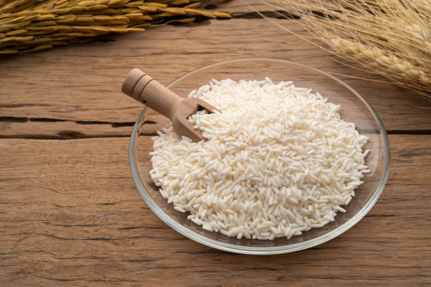 uncooked Thai sticky rice in glass plate on wooden table uncooked Thai sticky rice in glass plate on wooden table with copy space jasmine rice stock pictures, royalty-free photos & images